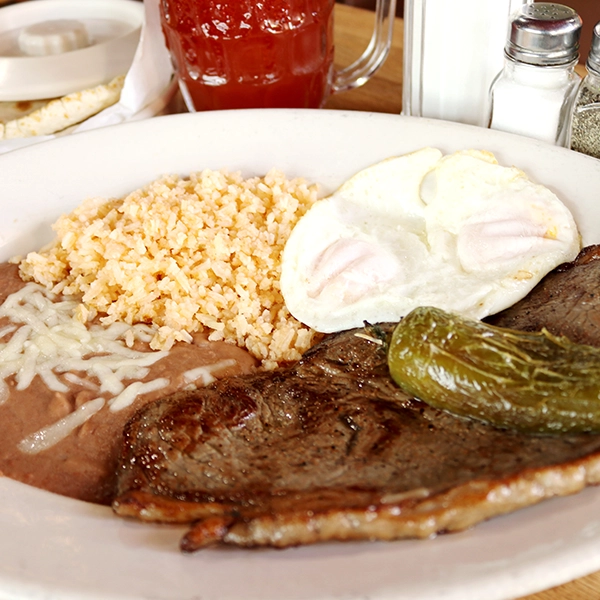 mexican style carne asada with a side egg, served with beans and rice