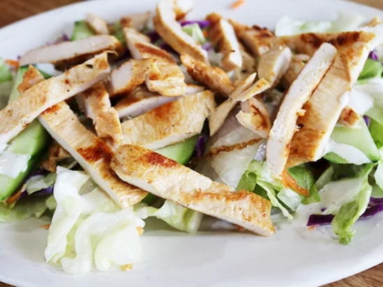 Grilled chicken fajitas on top of a lettuce salad