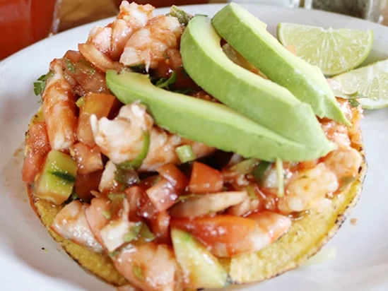 Mexican style shrimp ceviche in a corn chip tostada, with a garnish of avocado